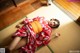 A woman in a red kimono laying on a tatami mat.