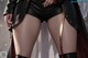 A woman's legs in black leather shorts and thigh-high boots with a gold strap.