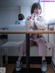 A woman sitting at a table with a cup of ice cream.