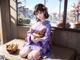 A woman in a kimono sitting on a bench with a bowl of food.