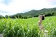 A naked woman sitting in a field of tall grass.