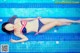 A woman in a bikini laying on the edge of a swimming pool.