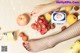 A woman's feet in fishnet stockings next to a variety of fruits.