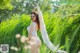 A woman in a white bodysuit standing in tall grass.