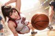 A woman in a basketball uniform holding a basketball on a court.