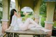 A woman in a white lingerie sitting on a wooden table.