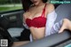 A woman in a red bra sitting in a car.