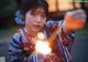 A woman in a kimono holding a light in her hand.