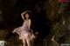 A woman in a floral dress standing in a cave.