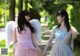 Two young women holding hands while walking in a park.