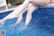 A woman's legs in a swimming pool with water splashing on them.